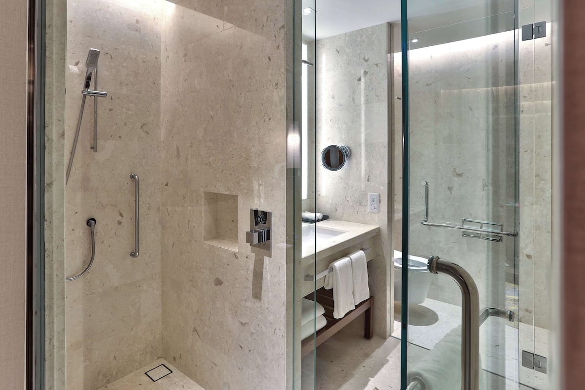 Ein modernes Badezimmer mit einer gläsernen Duschkabine, einem WC mit Glasabtrennung und einem Waschtisch mit Handtuchhalter.