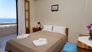 Ein Schlafzimmer mit einem Bett, einem Nachttisch, einem Schreibtisch, einem Stuhl, einem Fenster mit Vorhängen und einem Bild an der Wand.