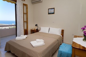 A bedroom with a bed, a nightstand, a desk, a chair, a window with curtains, and a picture on the wall.