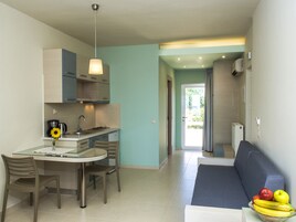 A modern kitchen with a dining area, a sofa, and a fruit bowl.