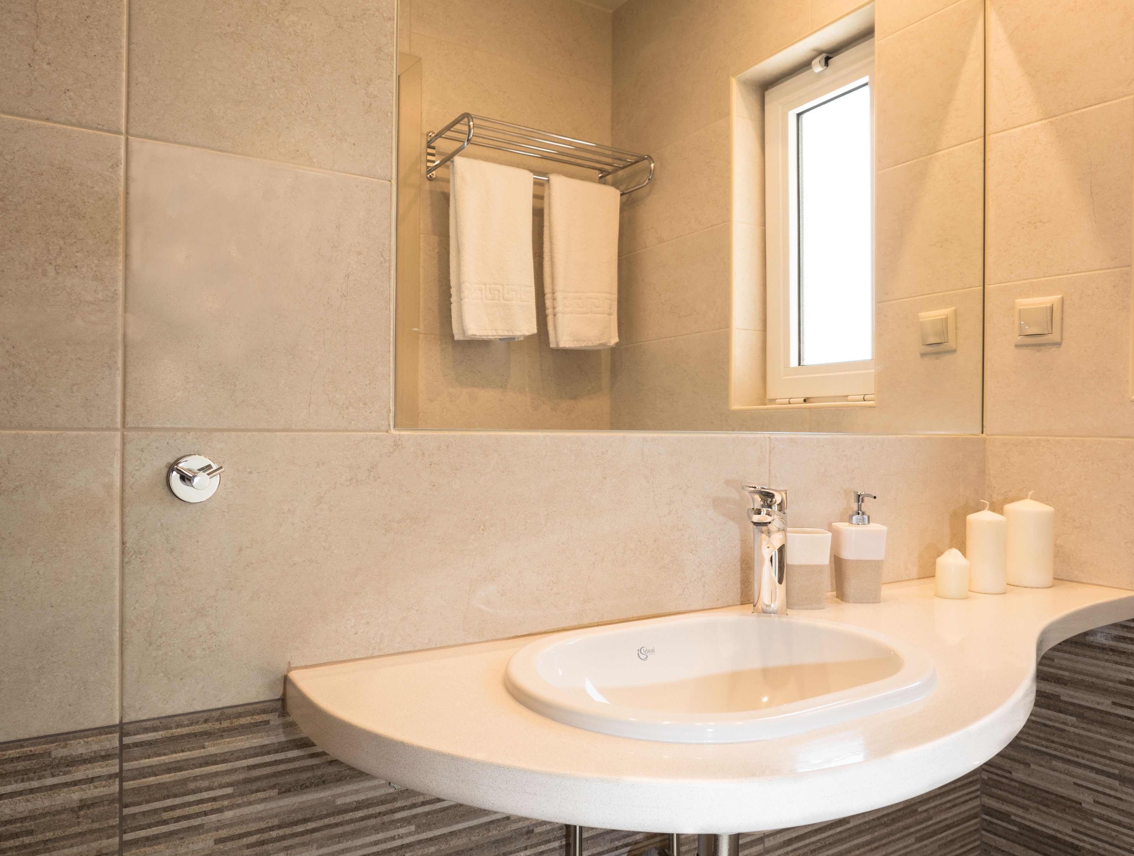 Une salle de bain moderne avec un lavabo incurvé, un miroir et une fenêtre.
