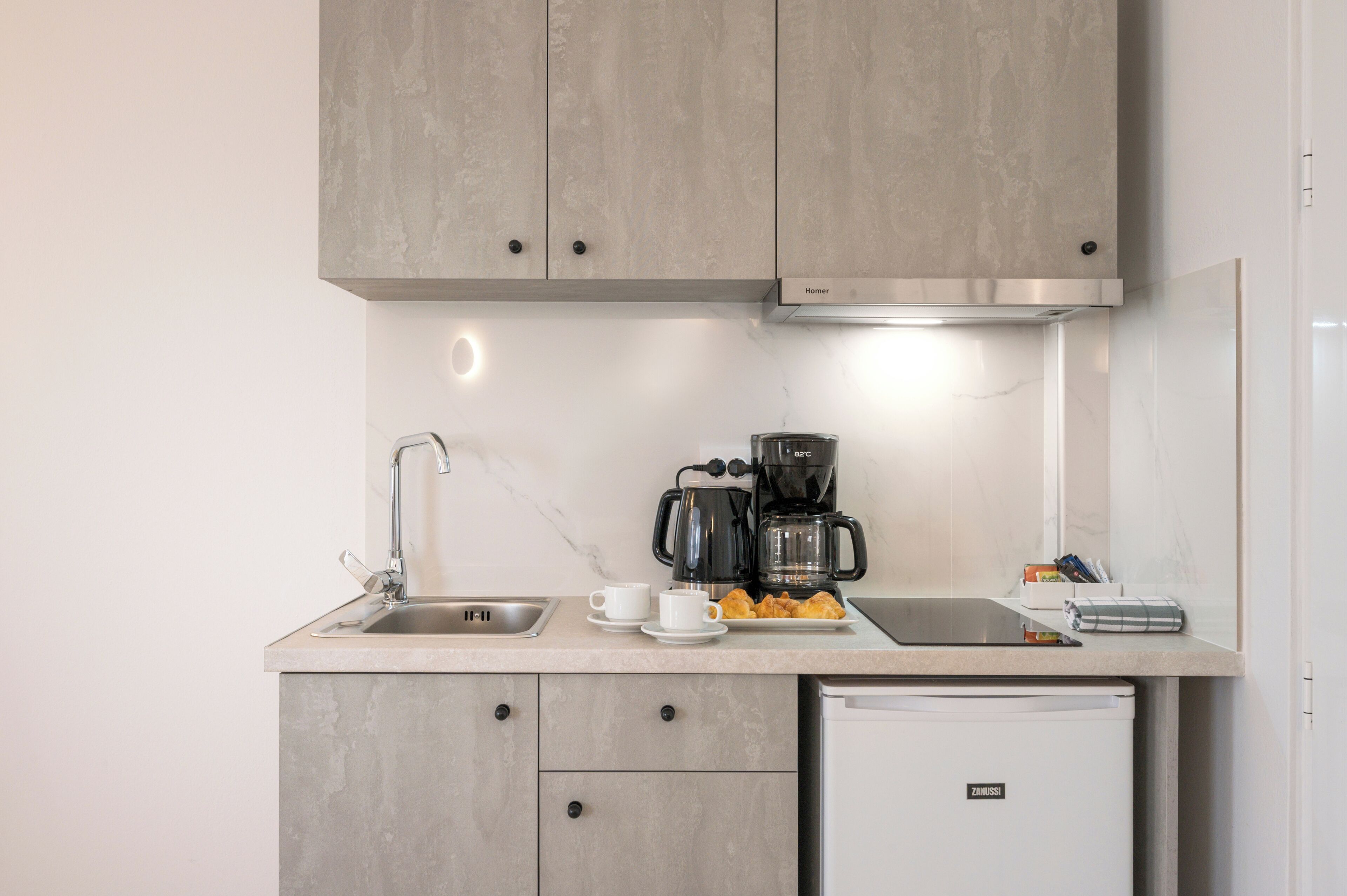 Uma cozinha compacta com cafeteira, pia e lava-louças.