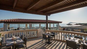 Una terraza con mesas dispuestas para comer, con vistas a una playa y al mar.