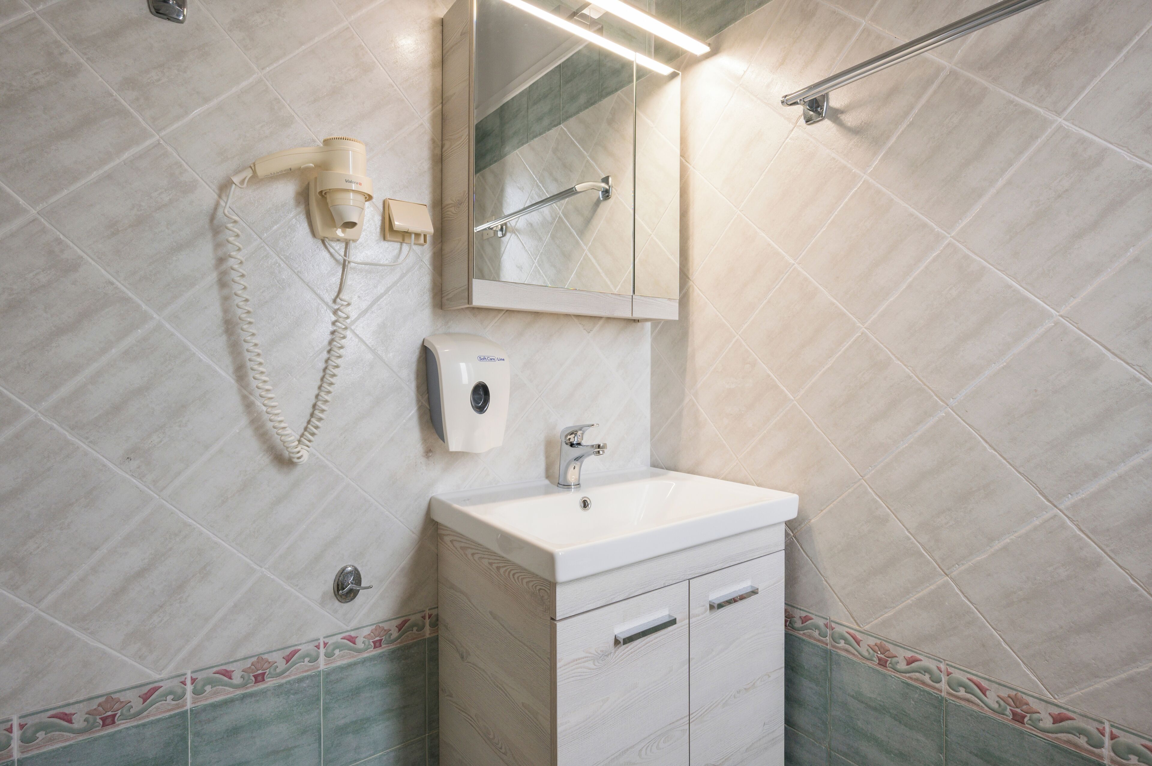 Un baño con lavamanos, espejo, toallero y secador de pelo.