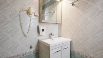 Un baño con lavamanos, espejo, toallero y secador de pelo.