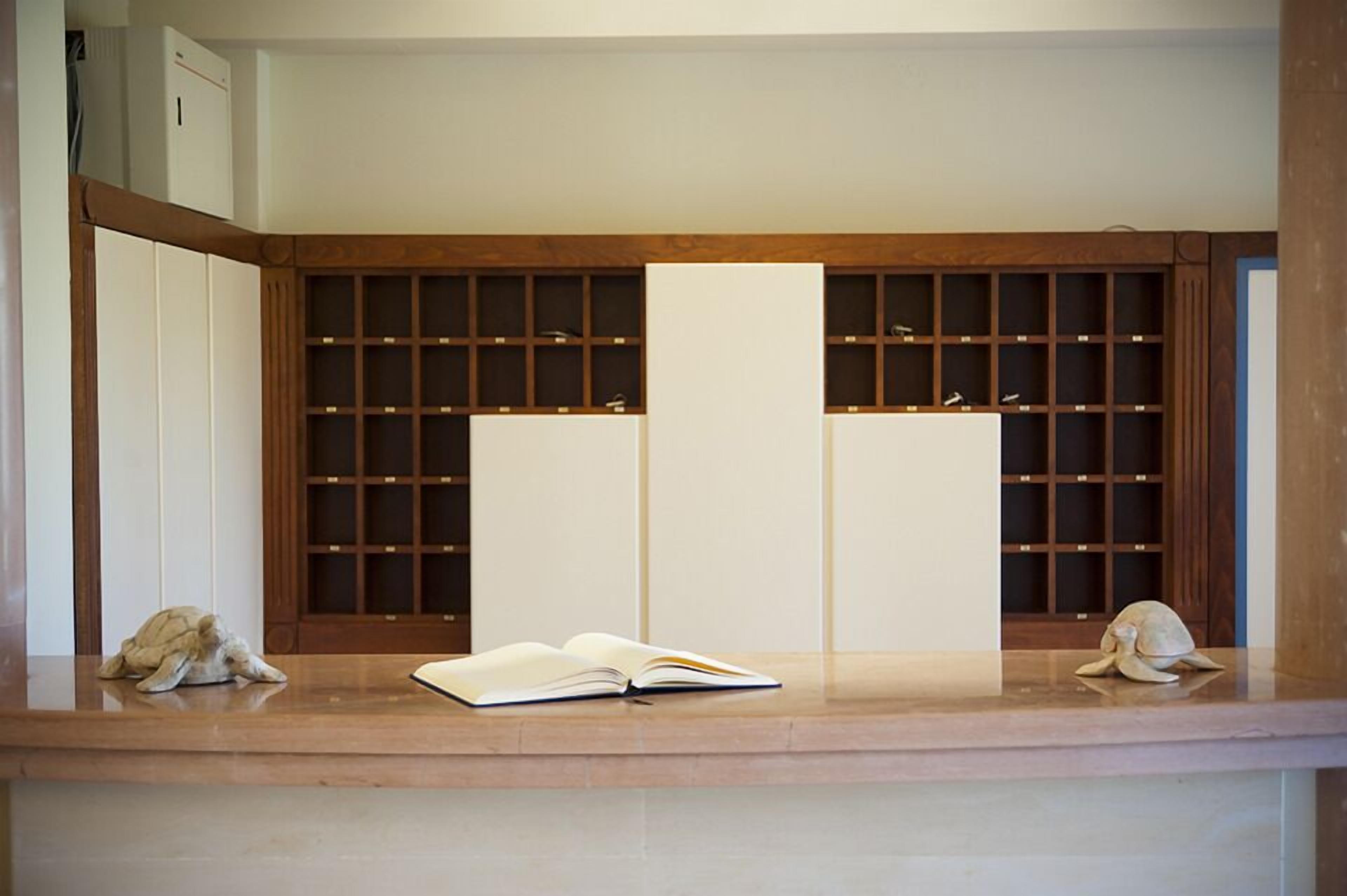 A reception desk with a wooden panel design, a white counter, and a book placed on it.
