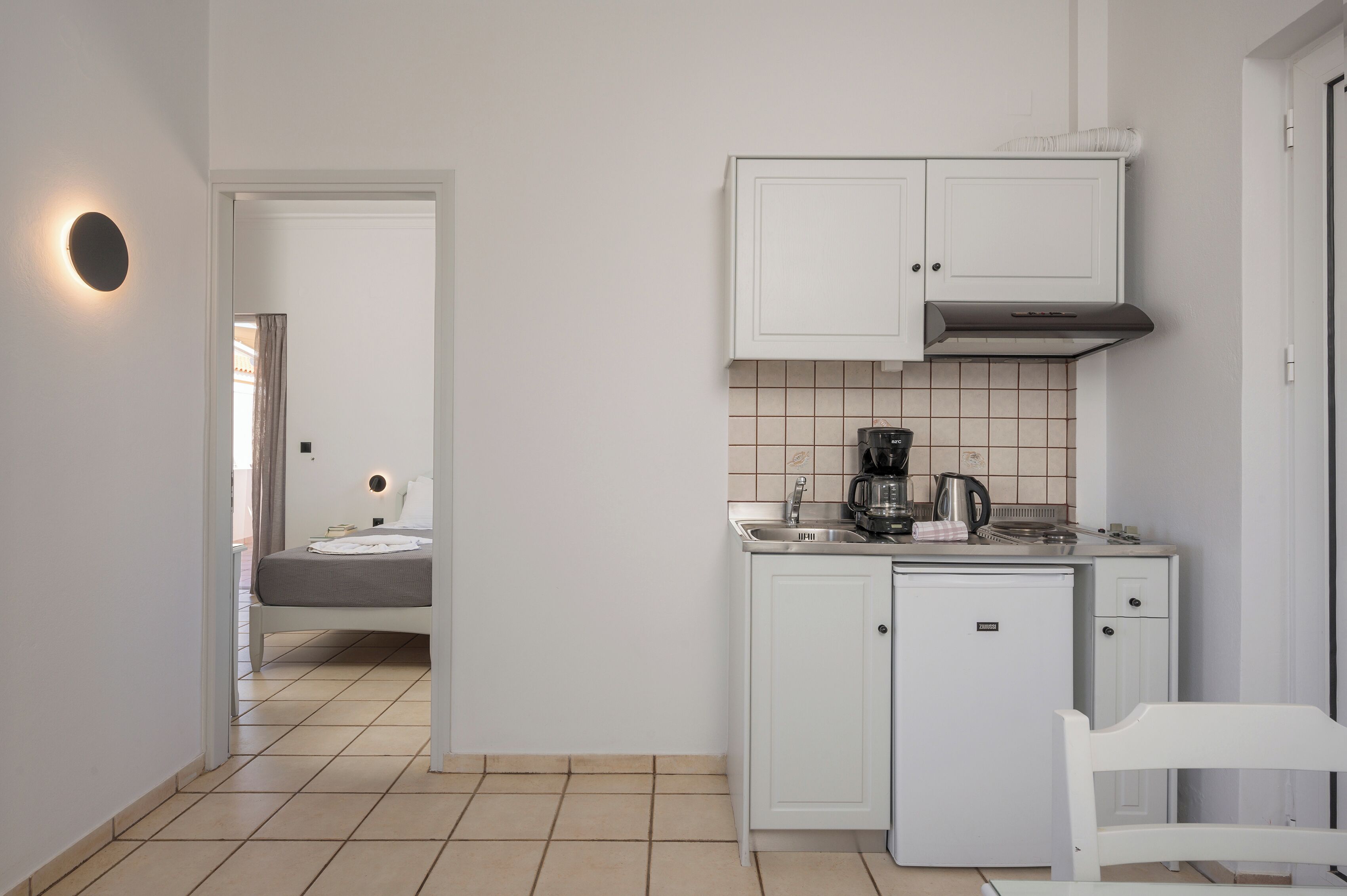 A compact kitchen with white cabinets, a small countertop, and a coffee maker.