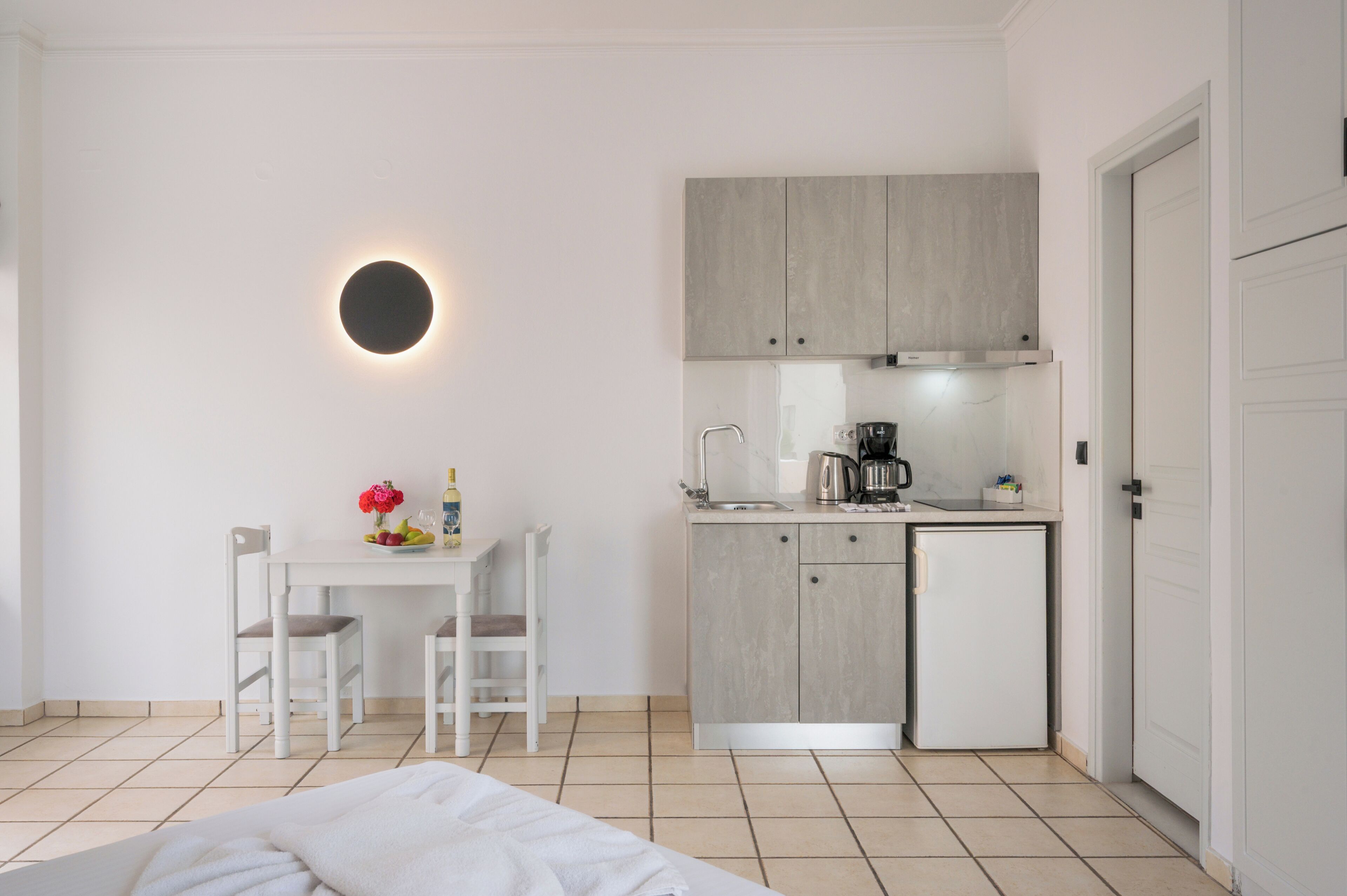 Une cuisine moderne équipée d’une cuisinière intégrée, d’un petit réfrigérateur et d’un évier. On y trouve également un coin repas avec une table et deux chaises.