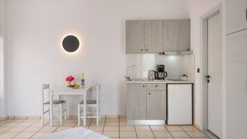Une cuisine moderne équipée d’une cuisinière intégrée, d’un petit réfrigérateur et d’un évier. On y trouve également un coin repas avec une table et deux chaises.