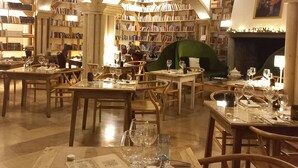 Una biblioteca con varias mesas dispuestas para comer, estanterías llenas de libros y una chimenea.