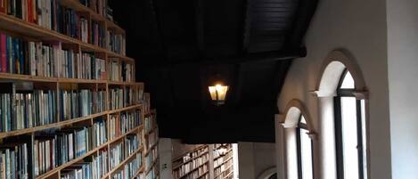 Une bibliothèque avec de hautes étagères, un plafond en pente et une grande fenêtre.
