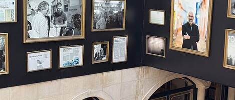 A gallery with framed photographs on the walls, a stone floor, and a glass ceiling.