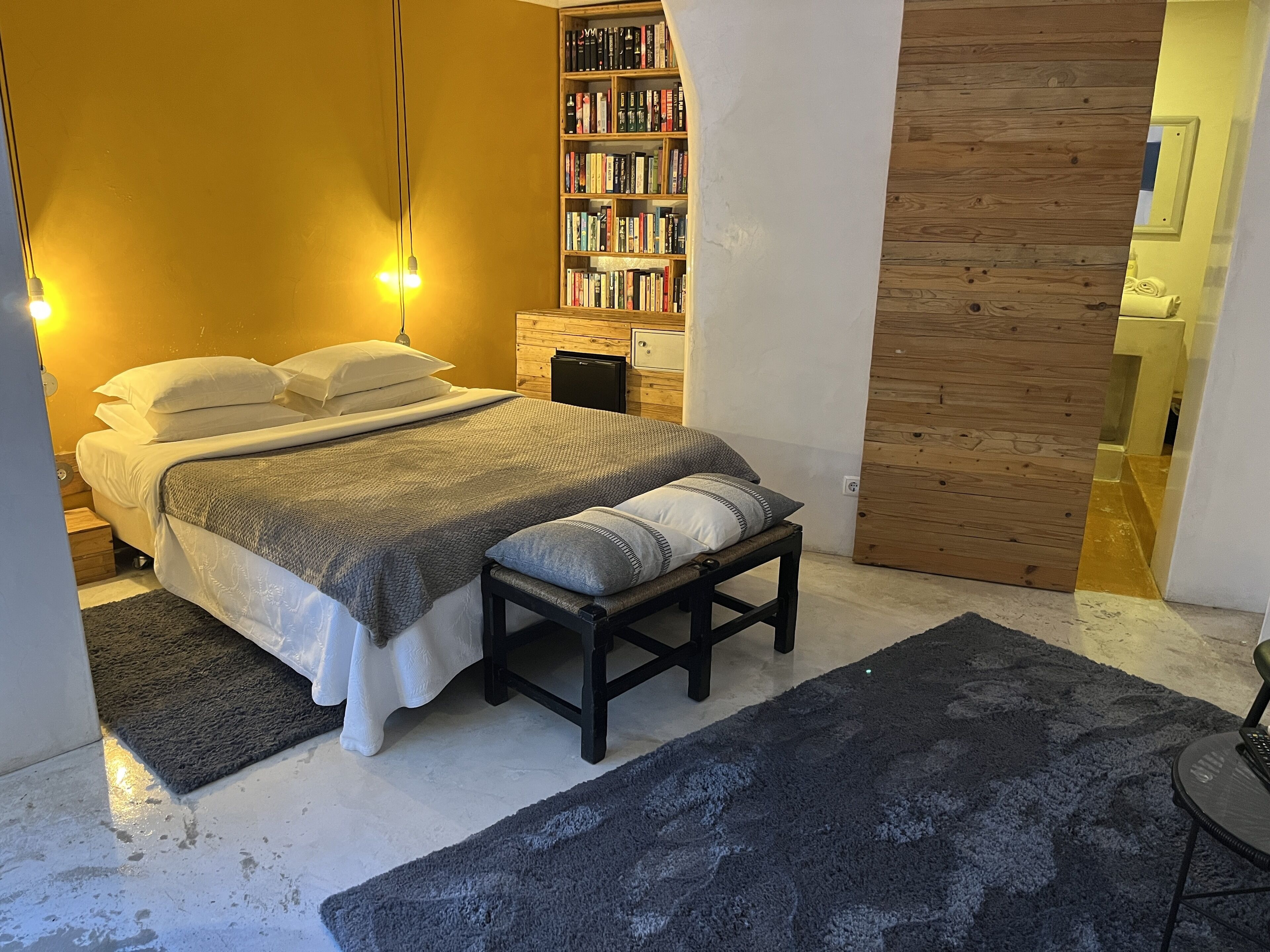 Une chambre à coucher avec un lit, des tables de chevet, une bibliothèque et un mur en bois.