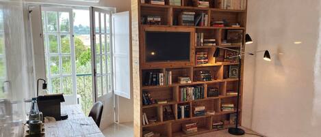 A room with a wooden bookshelf filled with books, a television, and a desk with a chair.