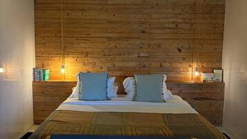 A bedroom with a wooden ceiling, a bed with blue bedding, and two bedside lamps.