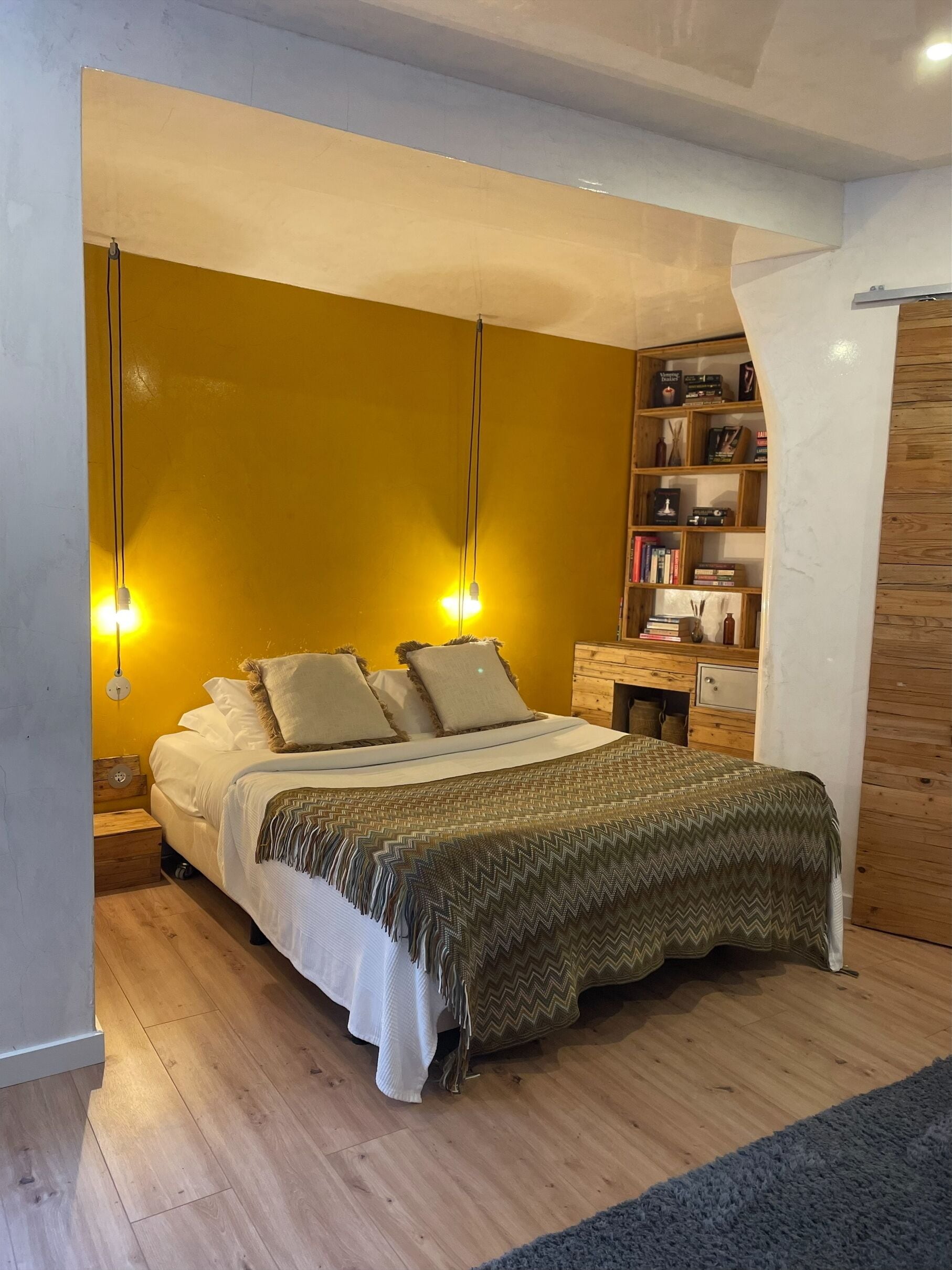 A bedroom with a bed, bedside tables, a bookshelf, and a wooden wardrobe.