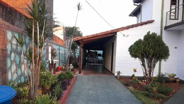 A narrow paved pathway leading to a covered entrance of a building with a tiled roof. - Nueva Alborada Lodging House (Fernando De La Mora)