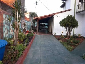A narrow paved pathway leading to a covered entrance of a building with a tiled roof. - Nueva Alborada Lodging House (Fernando De La Mora)