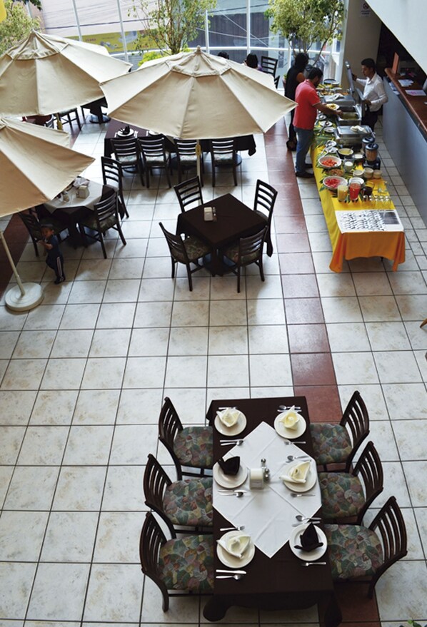 An outdoor dining area with multiple tables and chairs, some with umbrellas.