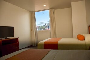 A hotel room with a bed, a TV on a wooden stand, and a window with curtains. - Hotel Mediterraneo (Tulancingo)