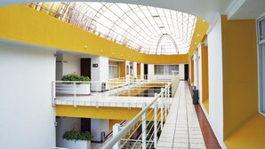 Ein mehrgeschossiges Interieur mit gelben und weißen Wänden, einer Glasdecke und einem gefliesten Boden.