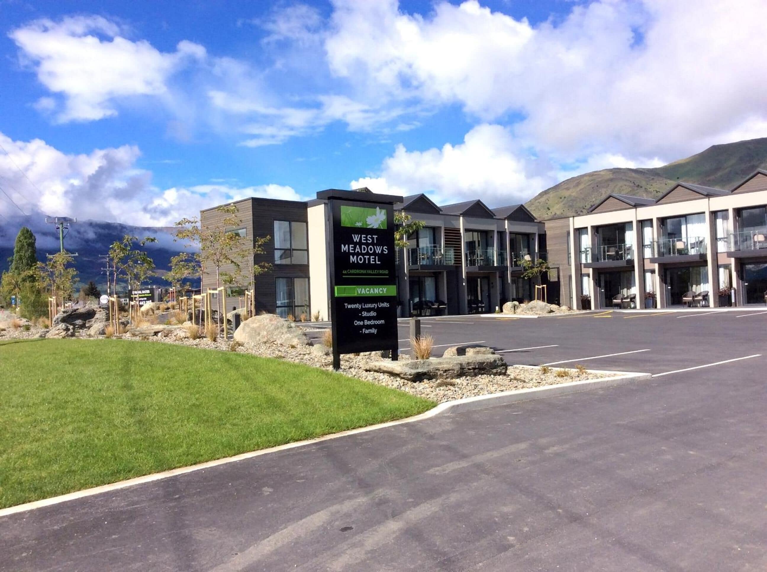 A modern motel with a sign indicating 20 luxury units, including studio, one-bedroom, and family rooms.