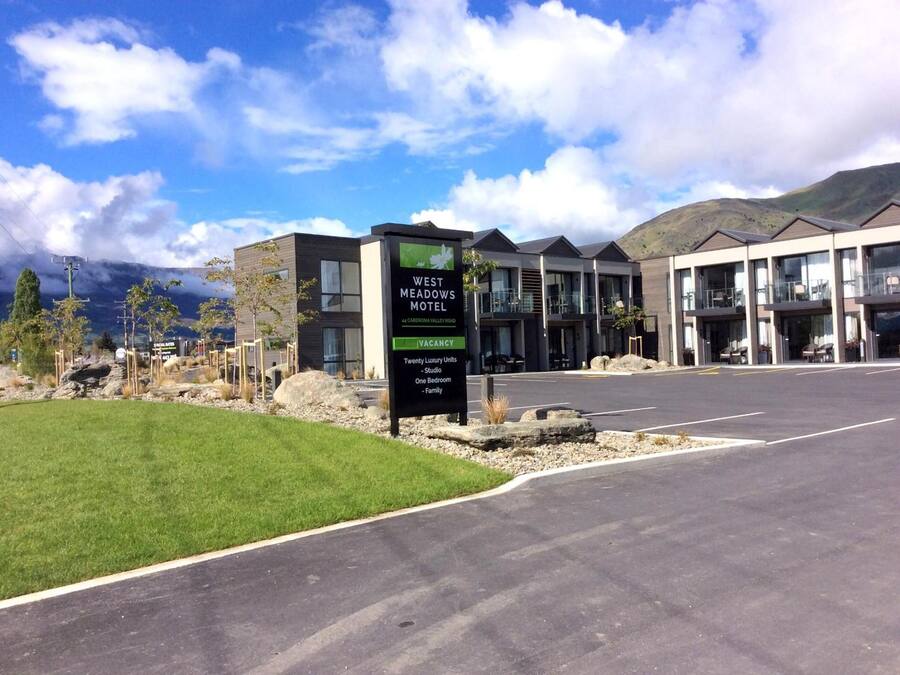 A modern motel with a sign indicating 20 luxury units, including studio, one-bedroom, and family rooms.