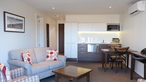 A modern living room with a sofa, a coffee table, and a dining area with chairs and a table. - West Meadows Motel (Wanaka)