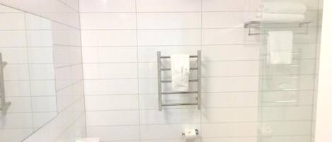 A modern bathroom with a toilet, sink, and glass shower enclosure.