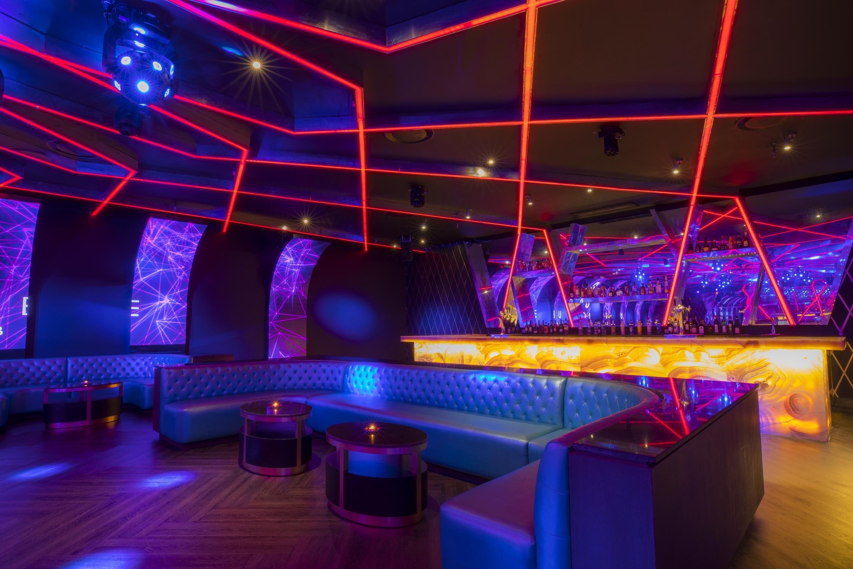 A modern lounge area with a bar, seating, and ambient lighting.