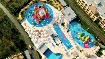 An aerial view of a resort with a large pool area, multiple water slides, and sun loungers.