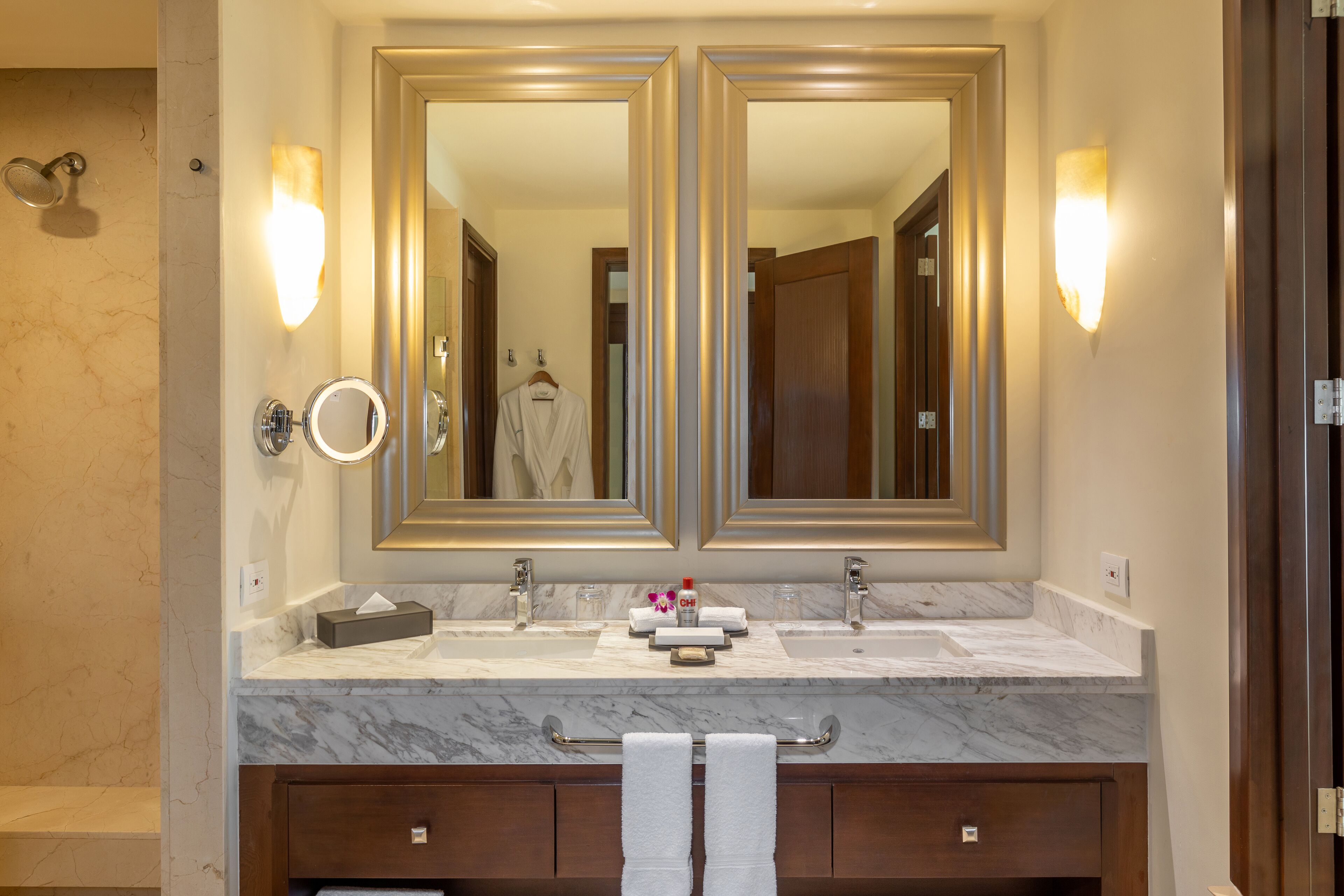 A bathroom with a double sink, two large mirrors, and a towel rack.