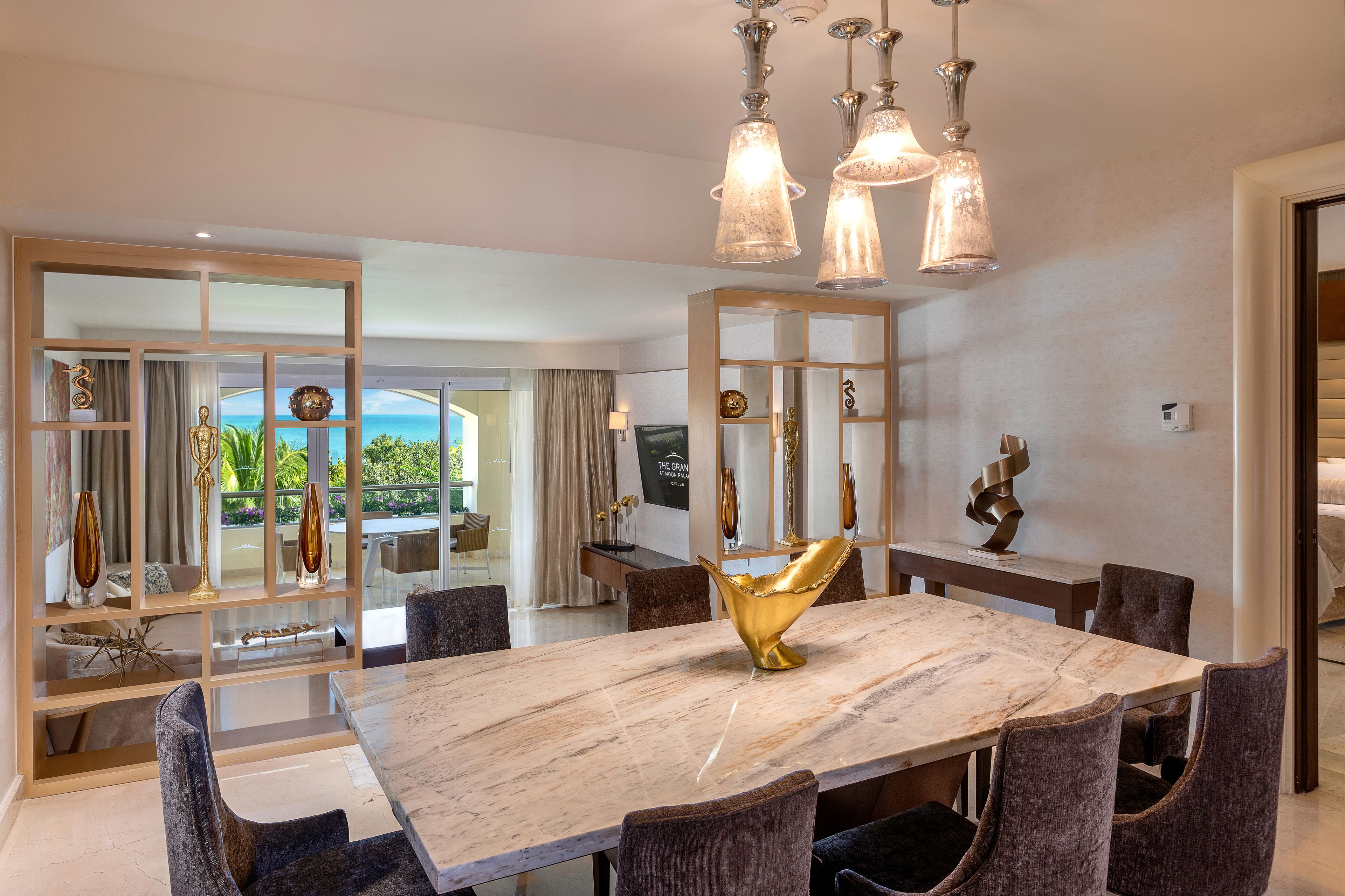 A dining area with a marble table, upholstered chairs, and pendant lighting.