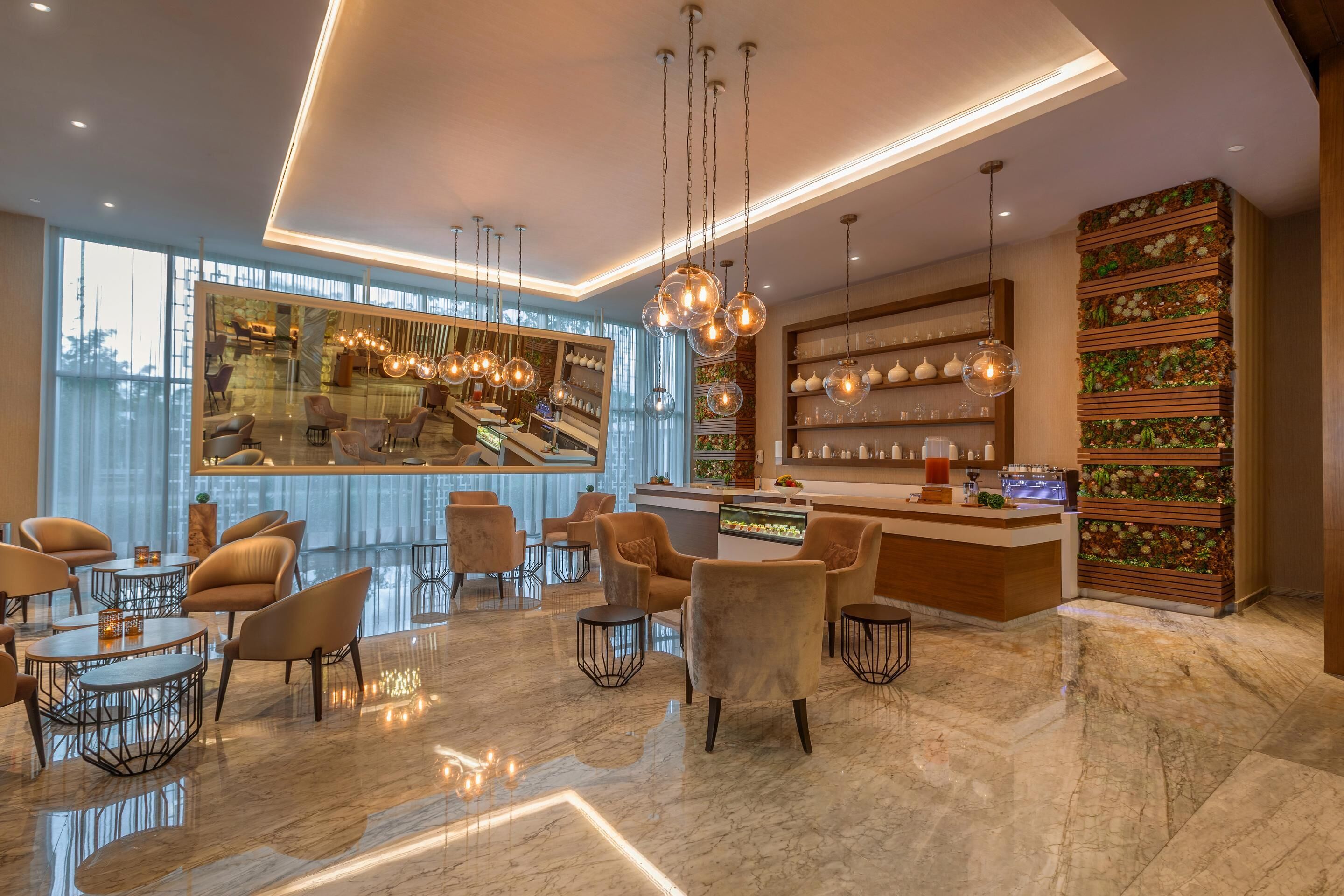 A modern hotel lobby with plush seating, a bar area, and a large window offering a city view.