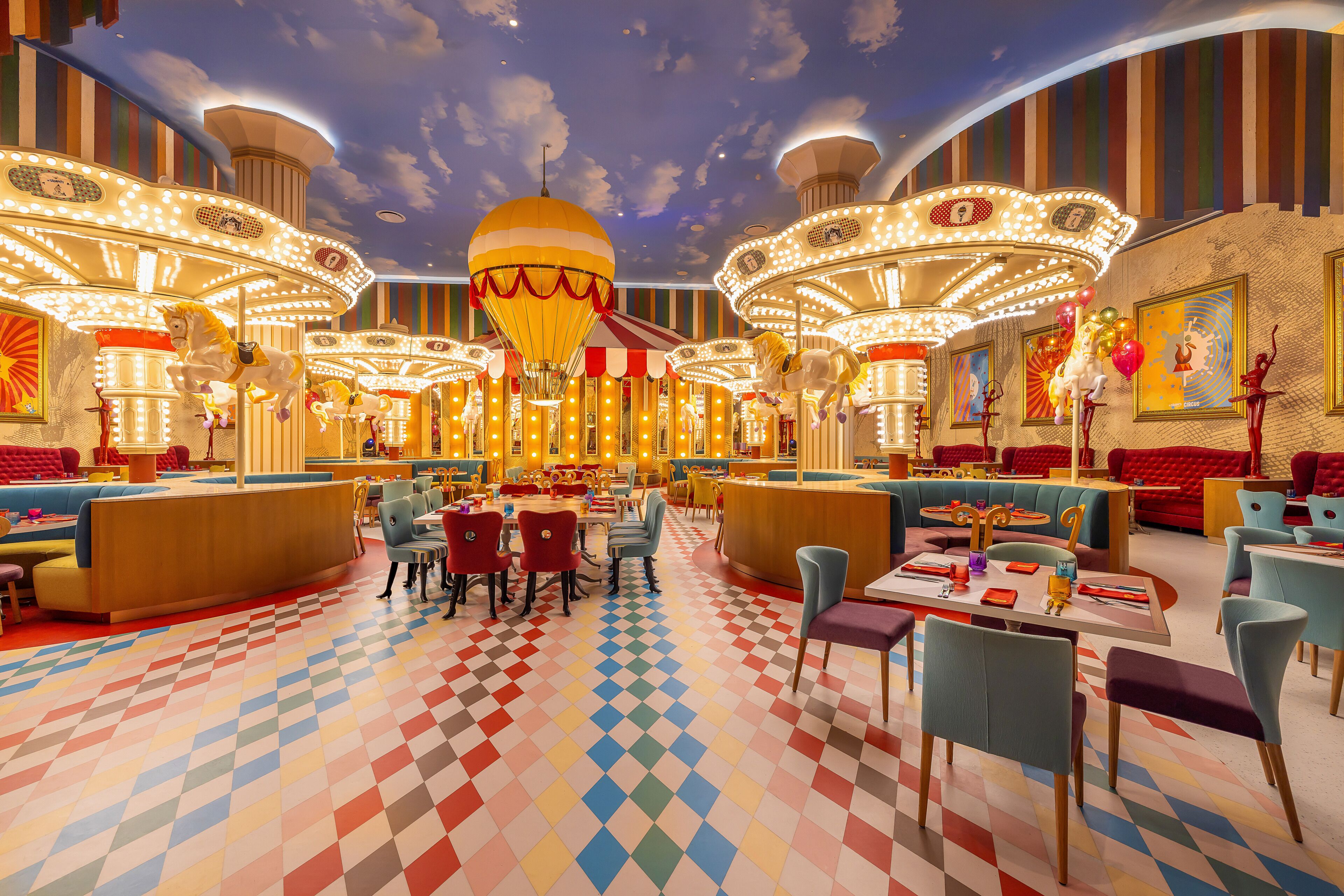 A carousel-themed restaurant with colorful checkered flooring and multiple seating areas.