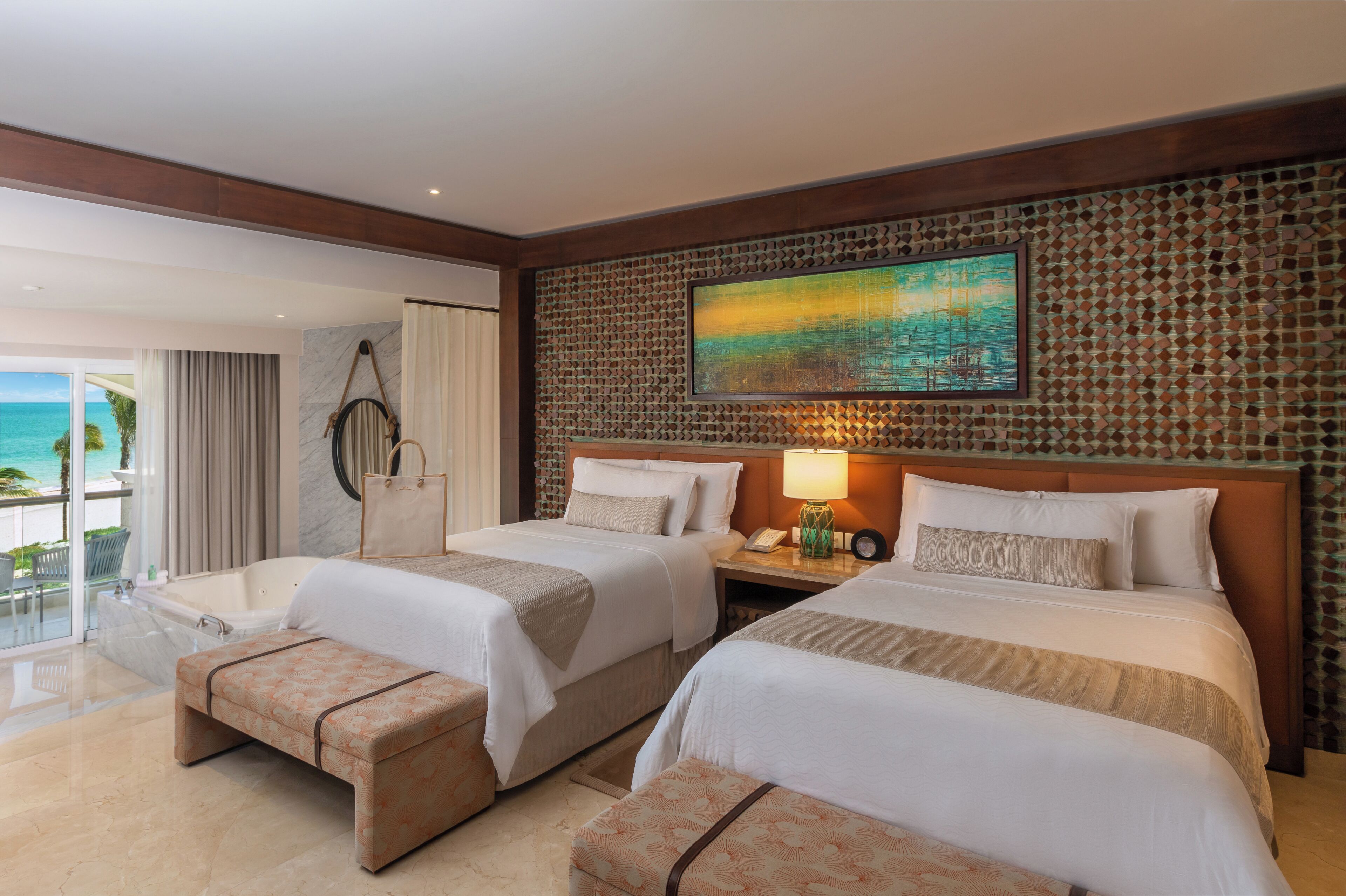A hotel room with two beds, a large window with a view of the ocean, and a decorative wall.