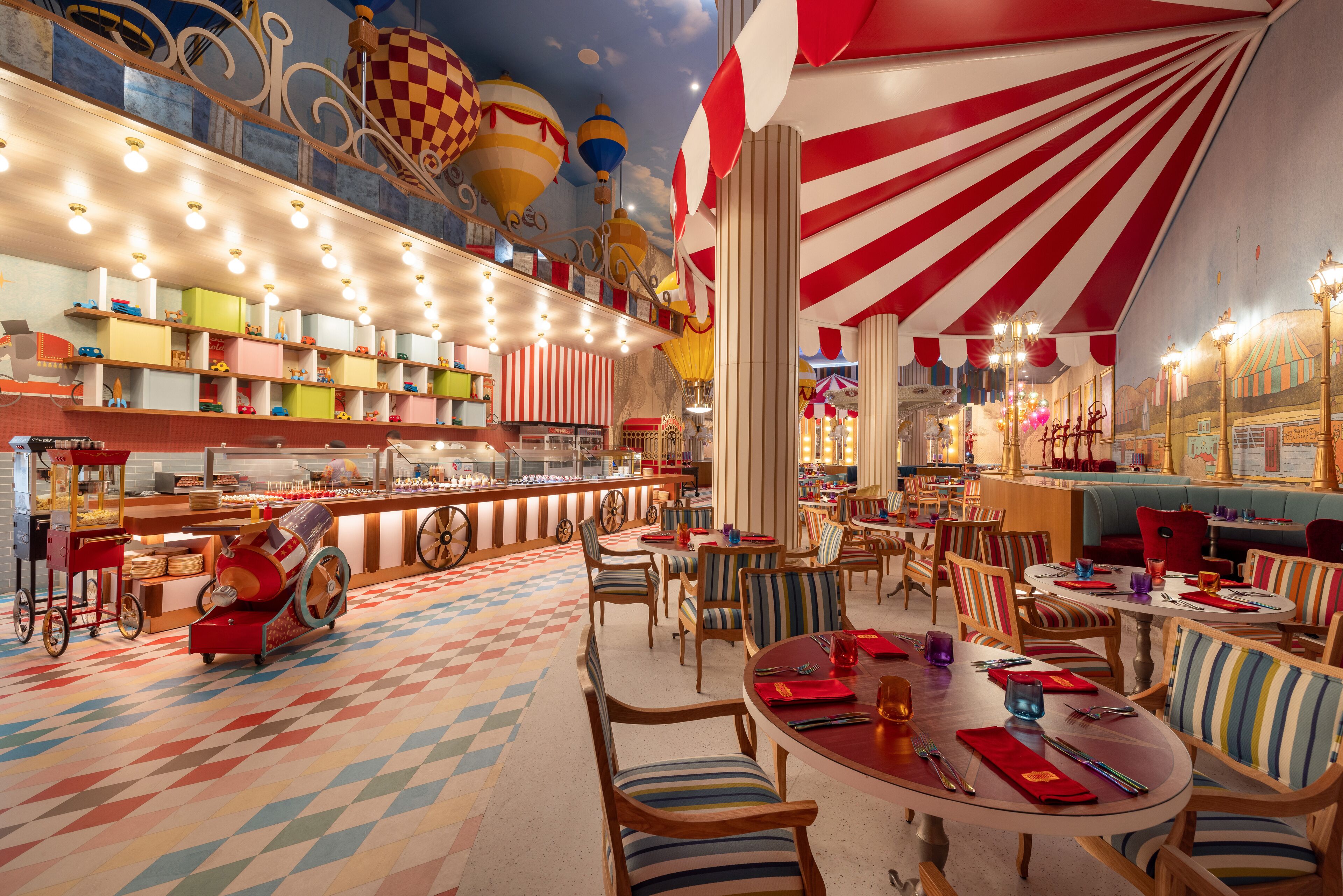 Un restaurant ple de vida amb seients de tiralls, una màquina de dolços i un paviment colorit.