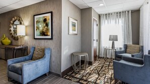 A hotel lobby with a modern design, featuring a blue sofa, a small round table, and a patterned carpet. - Quality Inn Pleasant View (Pleasant View)