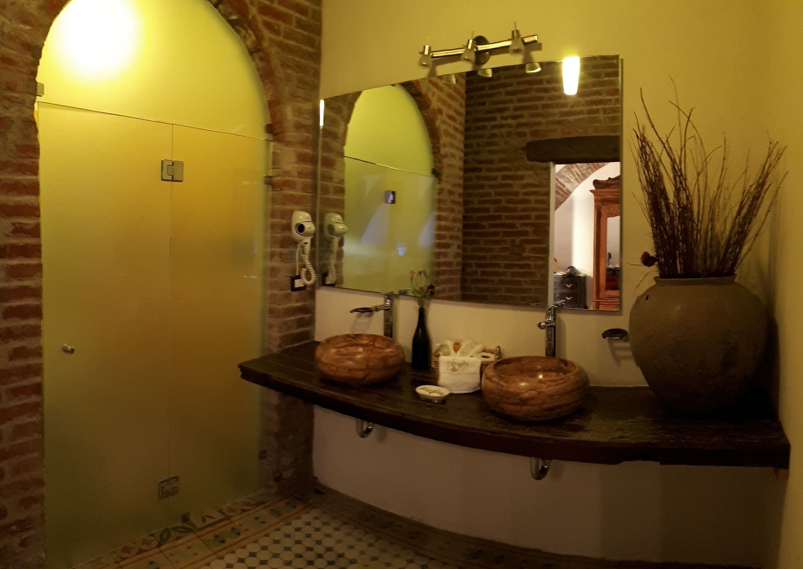 Ein Badezimmer mit Backsteinwand, gelber Tür, Spiegel, Waschbecken und Telefon.