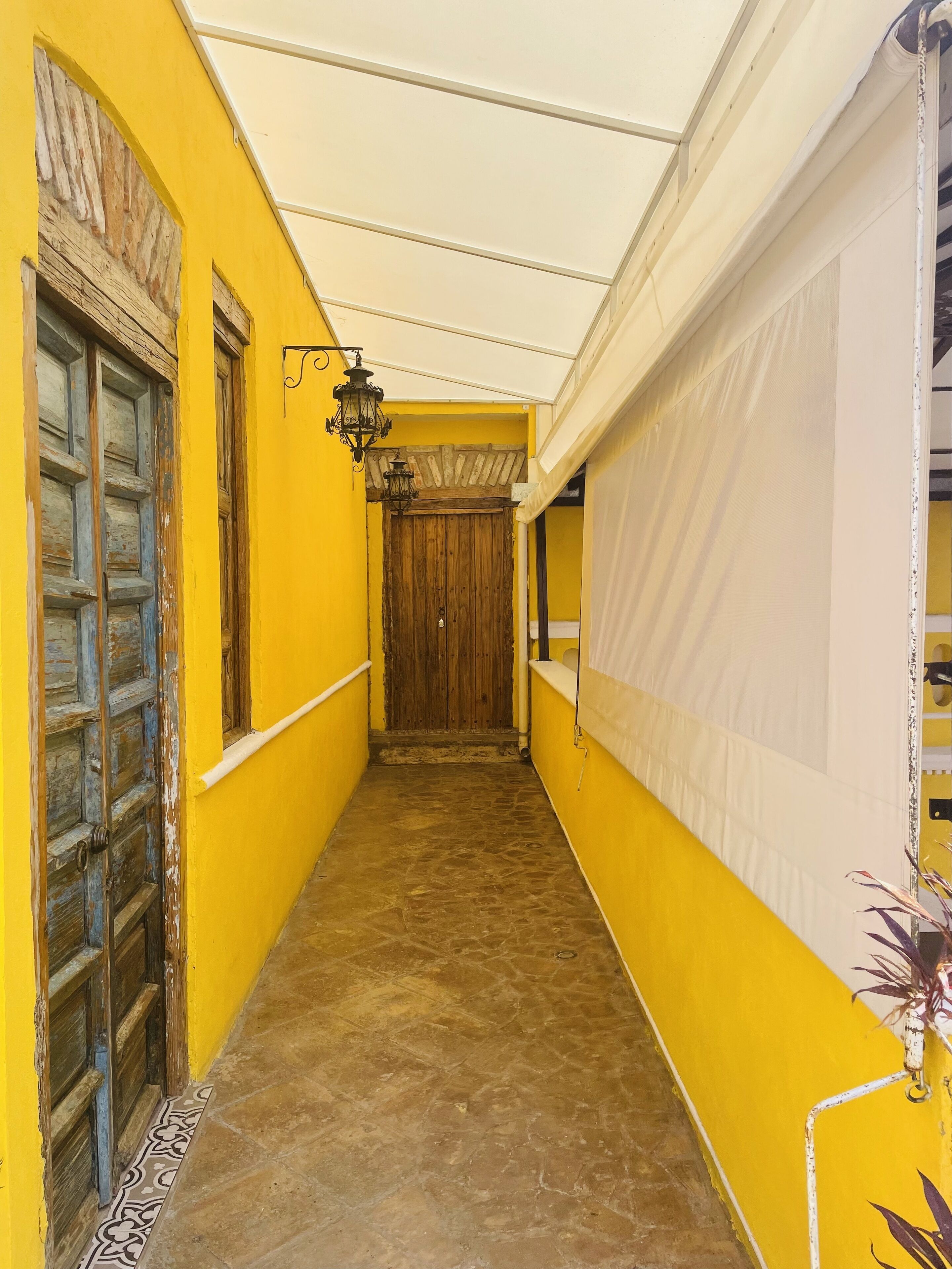 A narrow hallway with yellow walls, a wooden door, and a white ceiling.