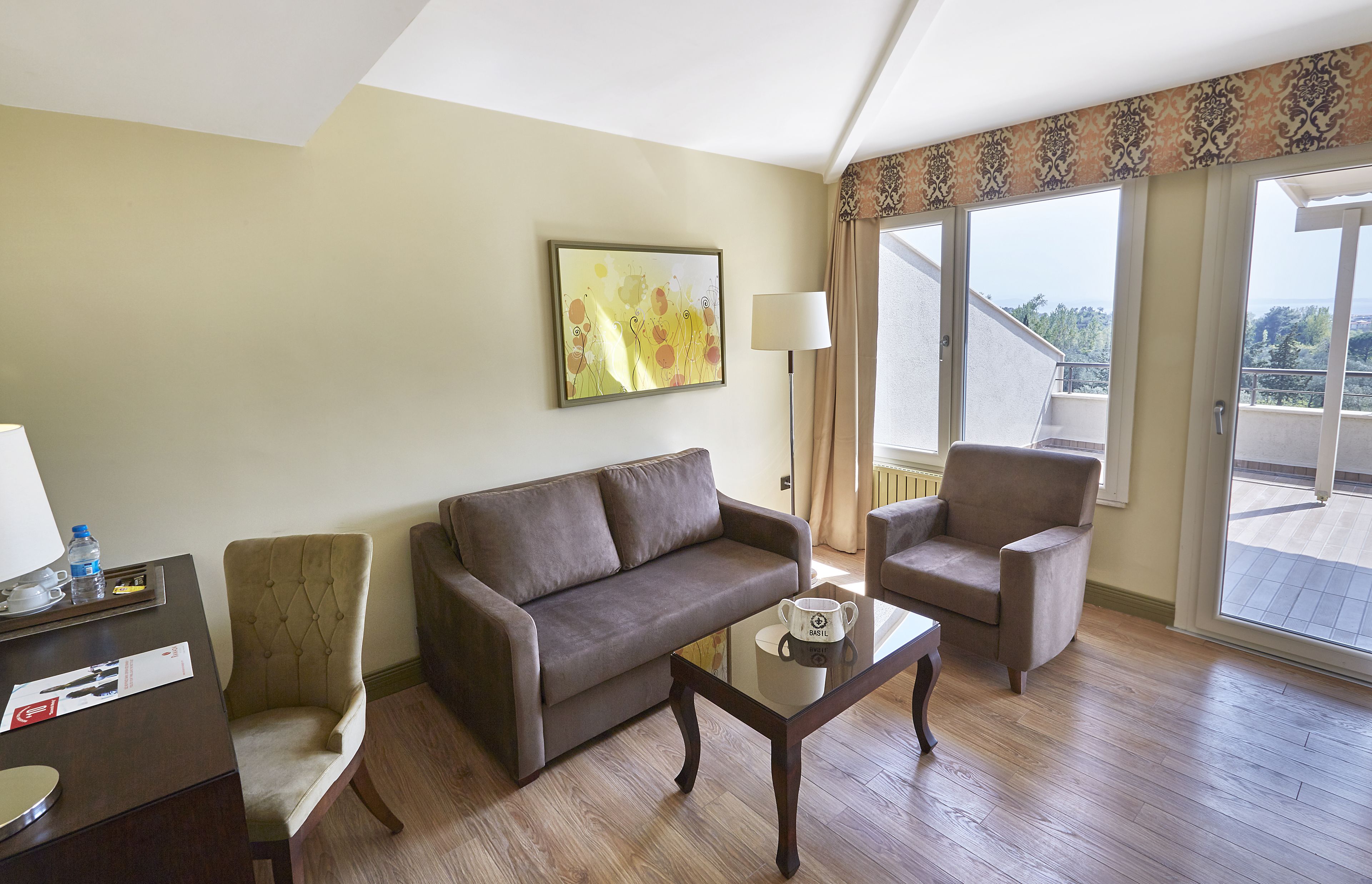 A hotel room with a sofa, armchair, and a coffee table.