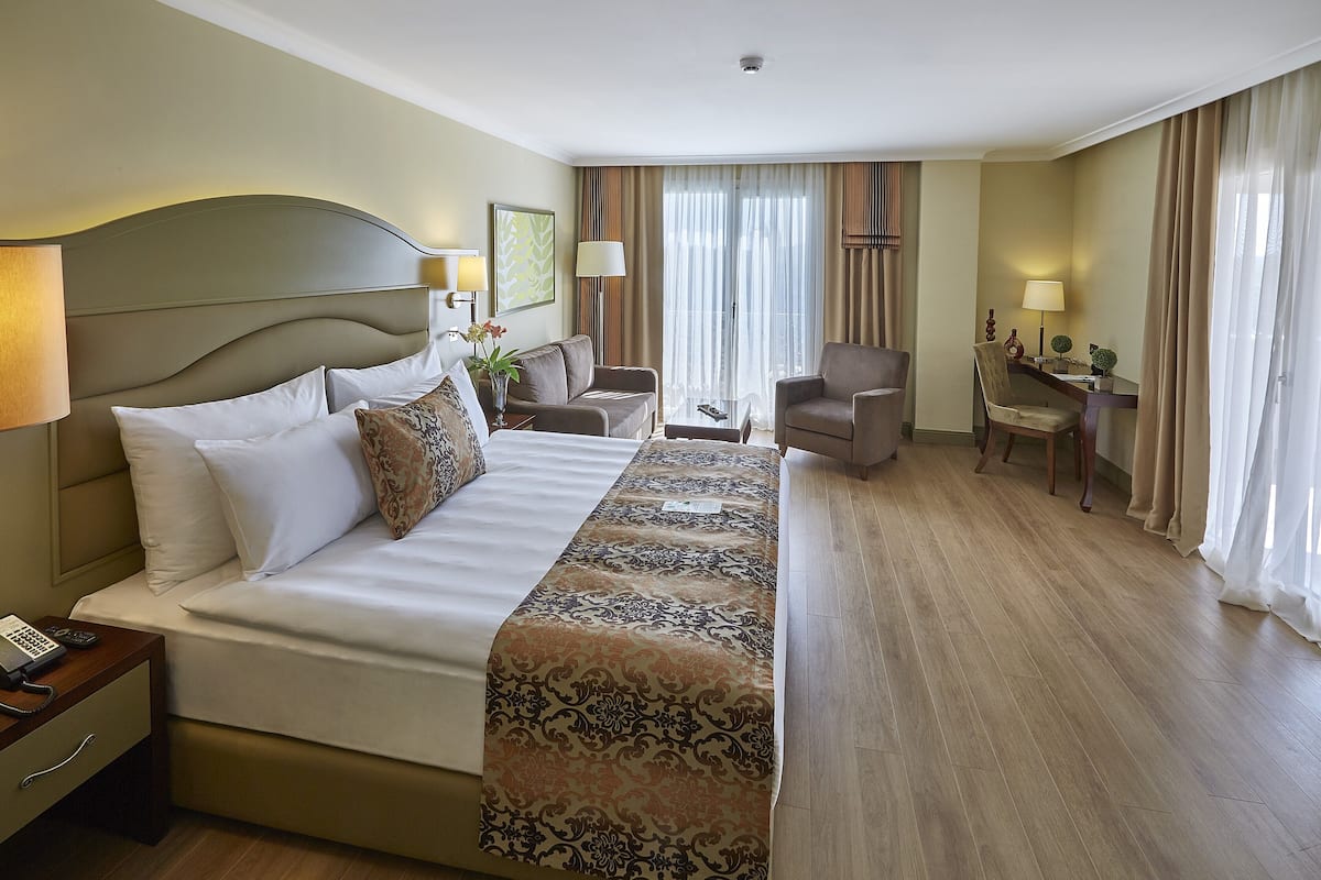 A hotel room with a large bed, two armchairs, a desk, and a chair.