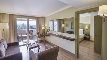 A hotel room with a balcony, a sofa, a desk, a chair, a bed, and a mirror.
