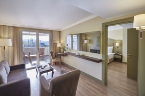 A hotel room with a balcony, a sofa, a desk, a chair, a bed, and a mirror. - Ramada Resort by Wyndham Kazdaglari Thermal and Spa (Edremit)