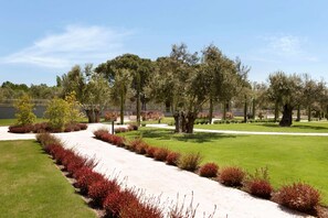 A landscaped garden with a paved walkway, trees, and neatly trimmed bushes. - Ramada Resort by Wyndham Kazdaglari Thermal and Spa (Edremit)