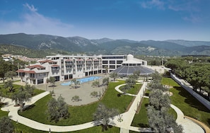 A modern hotel with multiple floors, a swimming pool, and a landscaped courtyard. - Ramada Resort by Wyndham Kazdaglari Thermal and Spa (Edremit)