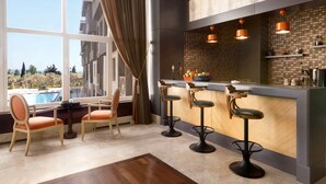 A modern bar area with a pool view, bar stools, and a wooden table.