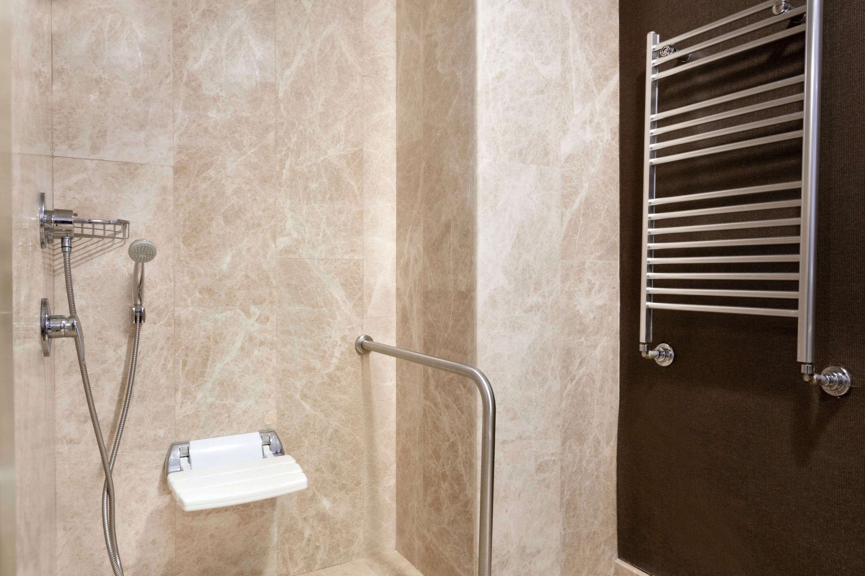 A bathroom with a shower, a towel rack, and a grab bar.
