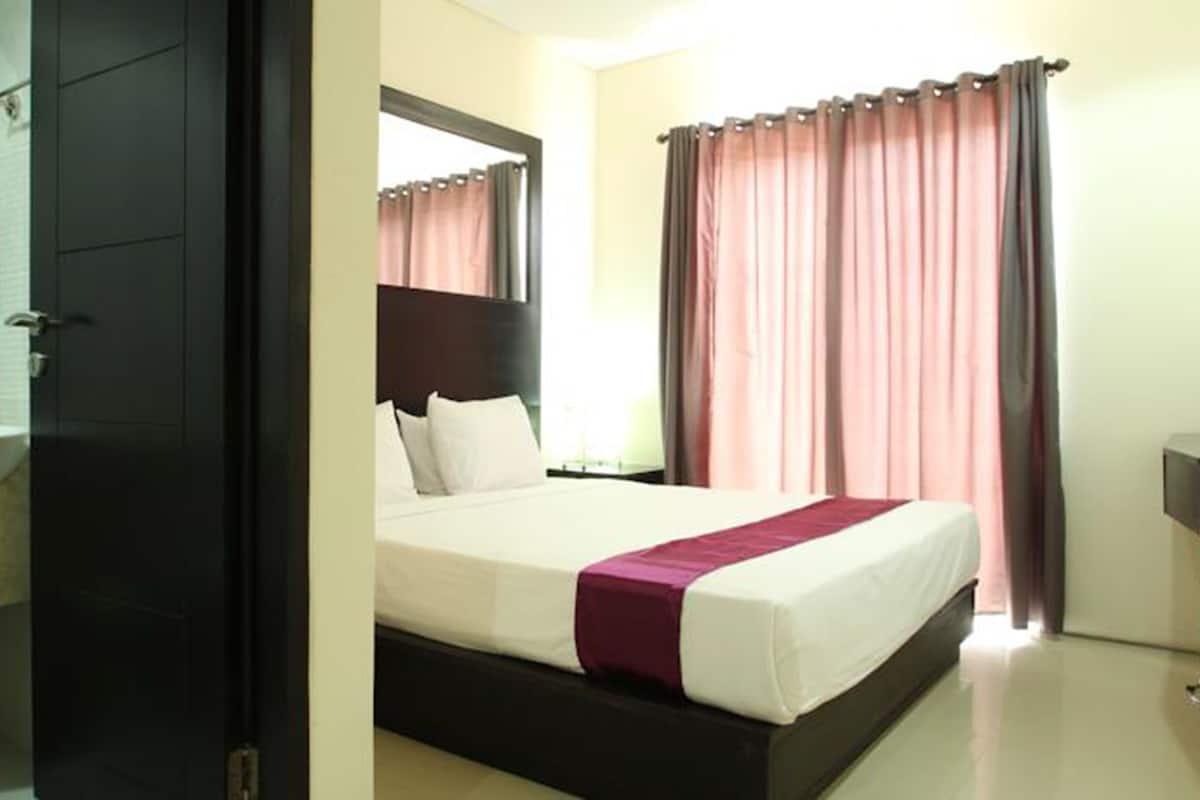 Une chambre d’hôtel avec un lit, une table de chevet, un miroir, un lavabo et des rideaux.