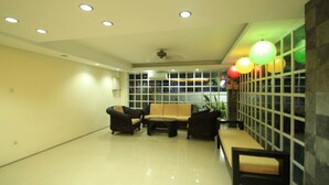 Een ruime kamer met een hoge plafond, inbouwverlichting, een zithoek met een bank en stoelen, en een groot raam met uitzicht.